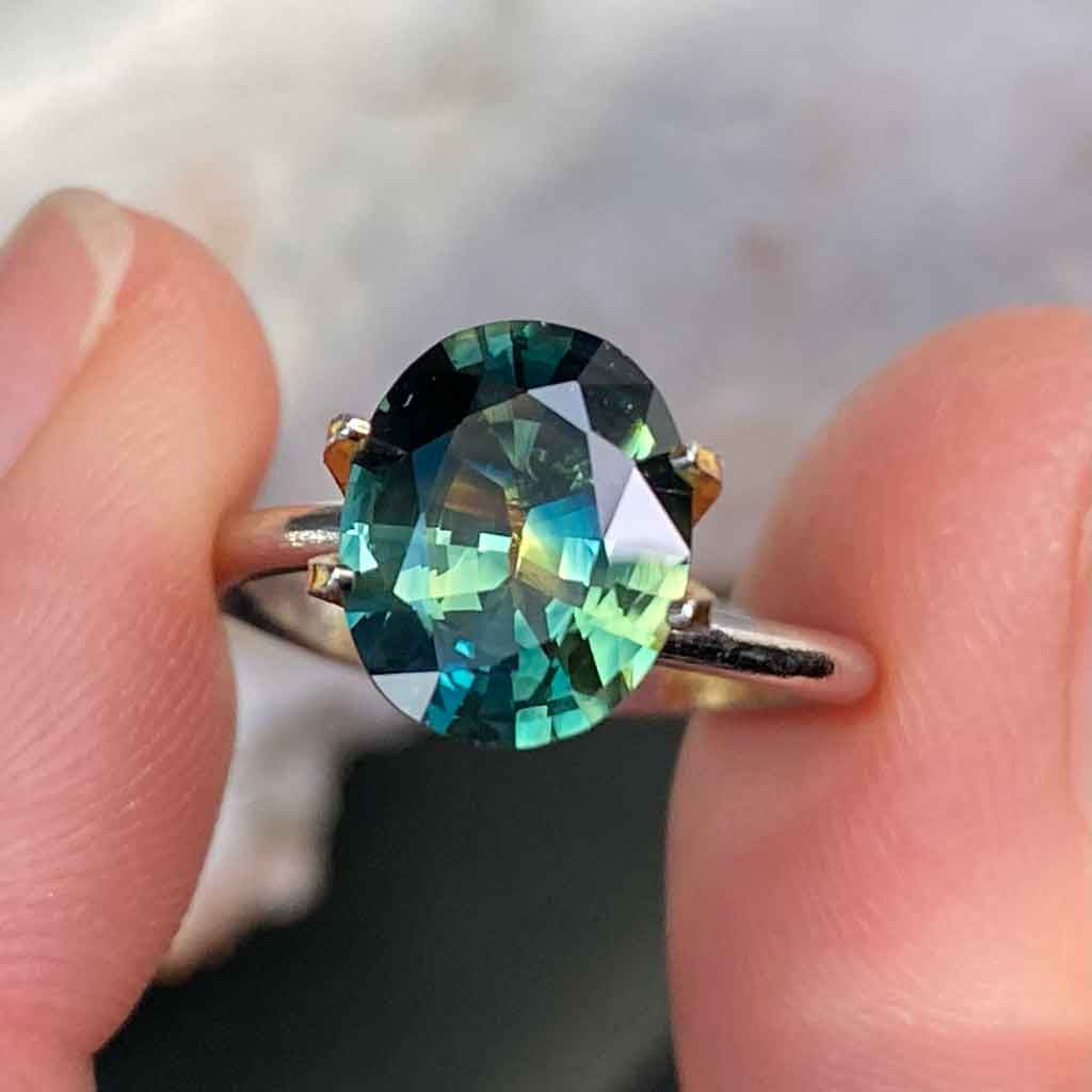 Oval Australian parti sapphire displaying blue, green and yellow colours, available to set in a bespoke engagement ring, by Sydney jeweller Lizunova