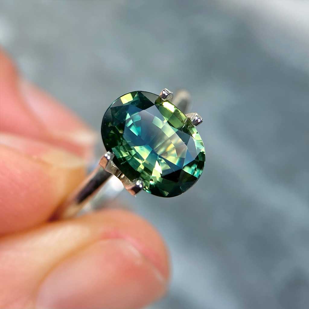 Oval Australian parti sapphire in blue, green, yellow colours, available to set in a sapphire engagement ring by Sydney jeweller Lizunova