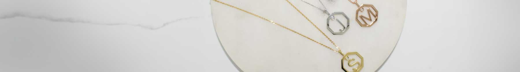 Three-inital-pendants-With-the Letter-S-J- and-M-lying-on-a-stone