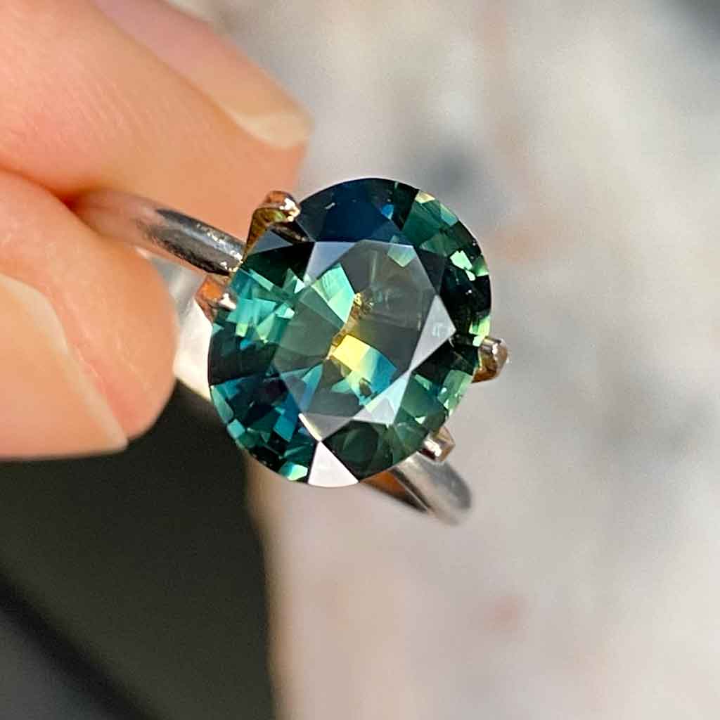 Oval Australian parti sapphire displaying blue, green and yellow colours, available to set in a bespoke engagement ring, by Sydney jeweller Lizunova