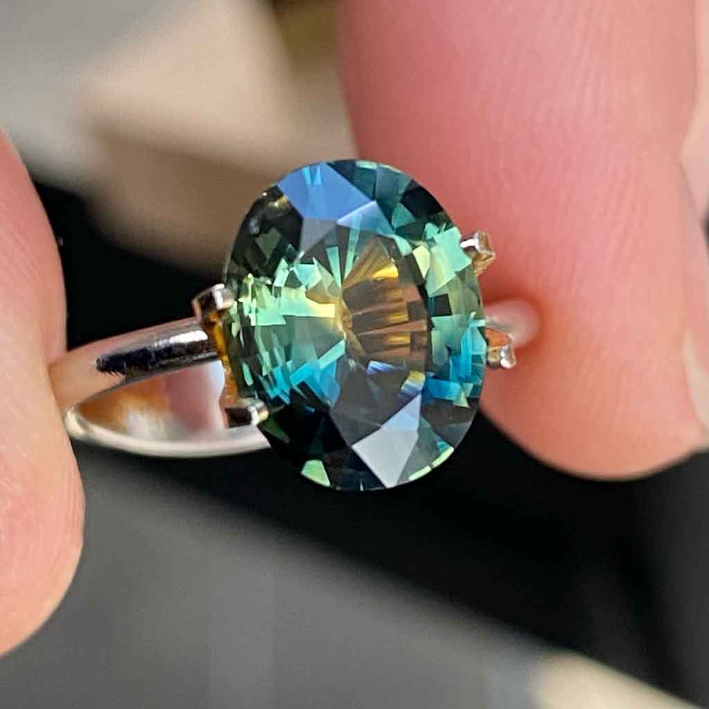 Oval Australian parti sapphire displaying blue, green and yellow colours, available to set in a bespoke engagement ring, by Sydney jeweller Lizunova