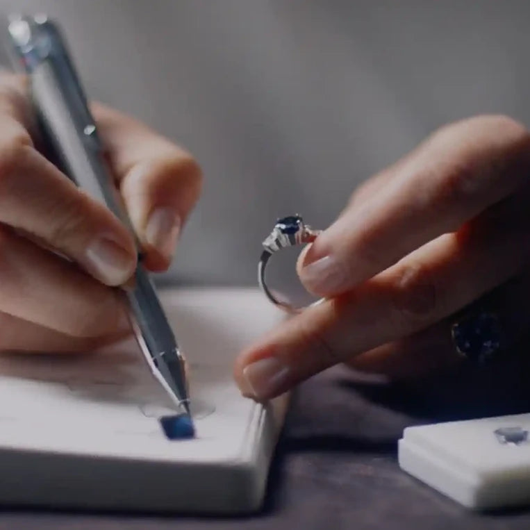 Bespoke Australian jewellery designer Maria Lizunova, of Lizunova Fine Jewels, sketching custom engagement ring designs, with loose sapphires and diamonds on the desk.