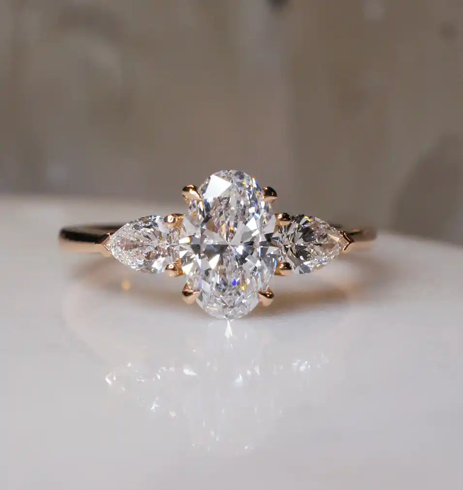 Three stone diamond engagement ring in 18k rose gold with a natural mined oval centre diamond, and two pear cut natural diamonds, handcrafted by Australian jeweller Lizunova Fine Jewels.